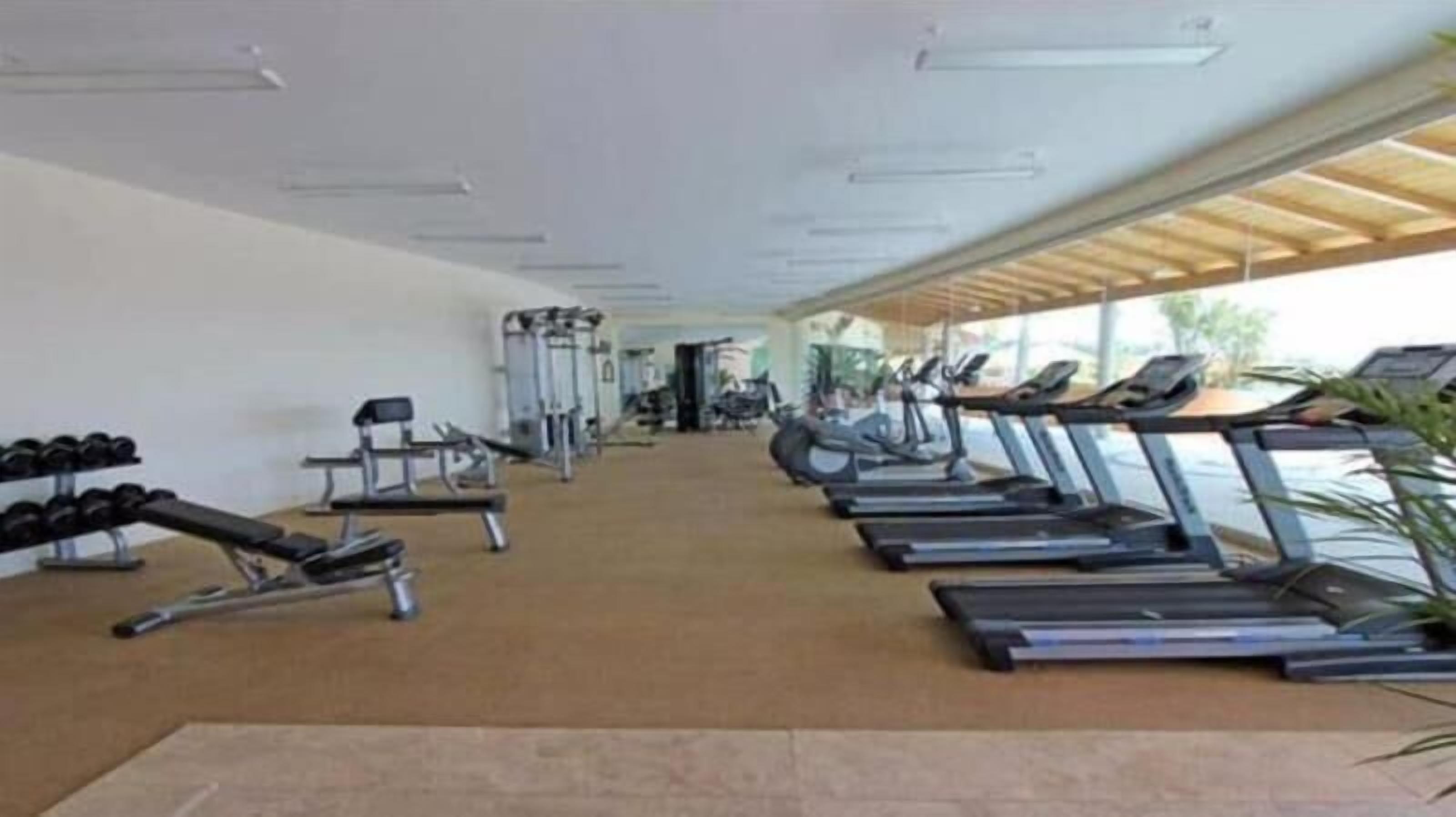 A gym with treadmills, dumbbells, and weight machines.