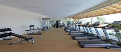 A gym with treadmills, dumbbells, and weight machines.