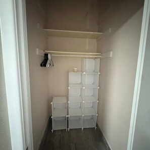 Een smalle gang met een witte opbergkast met verschillende vakken en een hangroede aan de linkerkant.