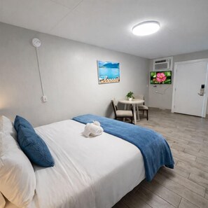 Een hotelkamer met een bed, een bureau, een stoel, een televisie en een deur.