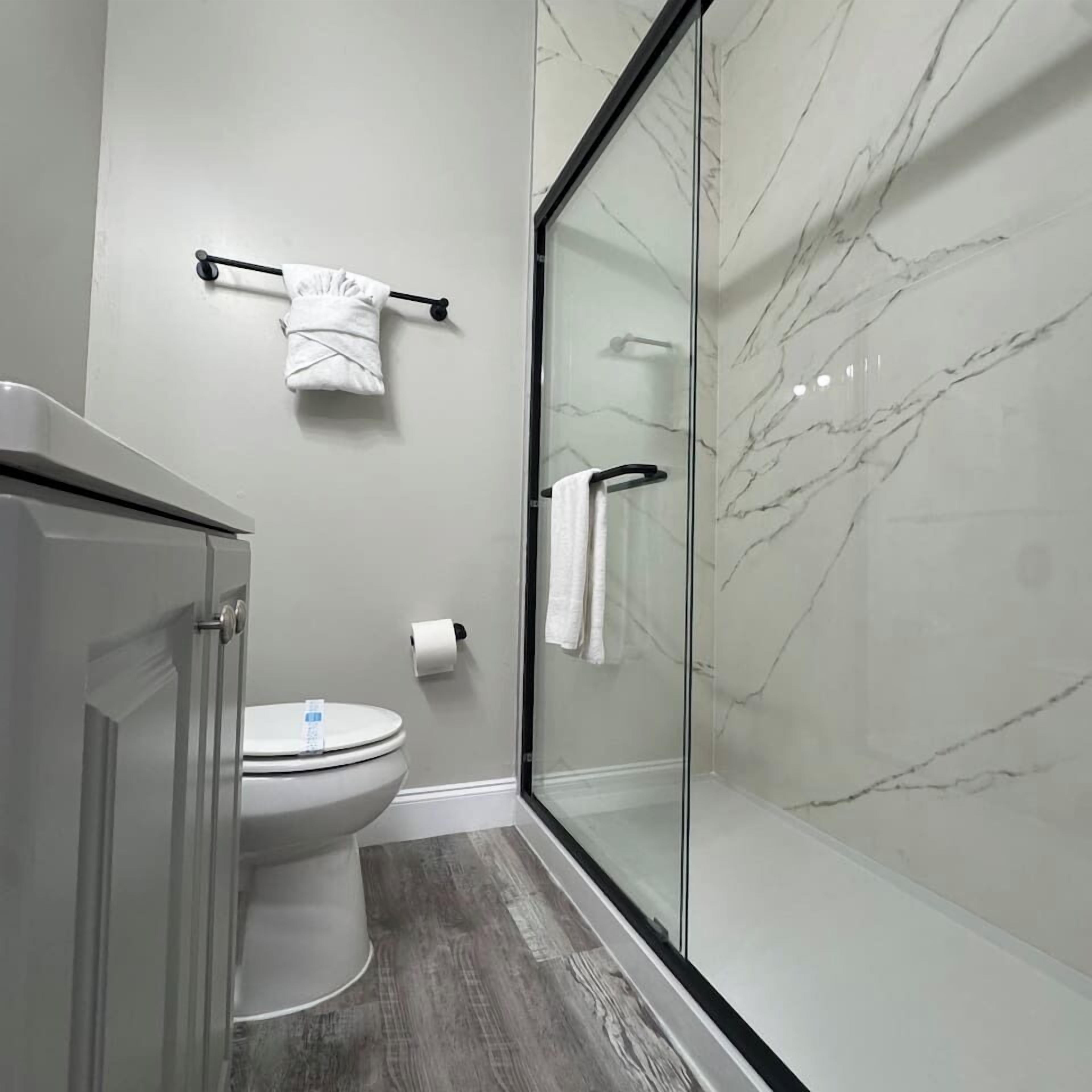 Une salle de bain moderne avec des toilettes, une douche à parois de verre et des murs en marbre.