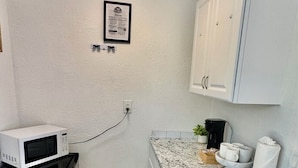 A compact kitchen with white cabinets, a microwave, a coffee maker, and a small sink. - Bright Coastal Stay • Pool • Near Beaches #3 (Clearwater)