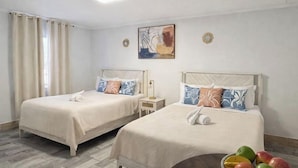 A hotel room with two beds, a wooden floor, a round table with fruit, and a painting on the wall. - Bright Coastal Stay • Pool • Near Beaches #3 (Clearwater)
