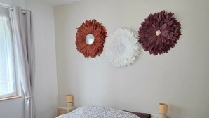 Quarto com cama, mesas de cabeceira e flores decorativas na parede.