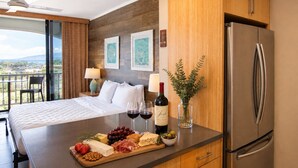 A hotel room with a bed, a breakfast bar with cheese, grapes, and wine, a refrigerator, and a view of the outdoors. - Holo Hou Hale - Lahaina Shores Retreat on Front St (Lahaina)