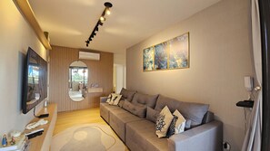 A modern living room with a grey sofa, a flat-screen TV, a mirror, and a ceiling light fixture. - Luxury penthouse apartment with air conditioning in all rooms in Ubatuba. (Ubatuba)