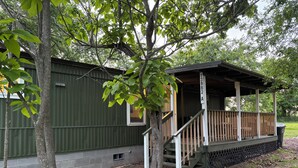 A small, single-story building with a covered porch and a staircase leading to an upper level.