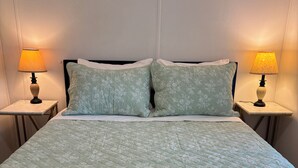 A bed with a quilted floral pattern, two bedside lamps, and a headboard.