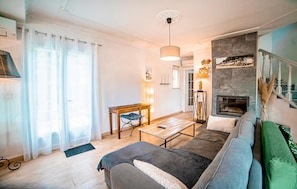 Ein Wohnzimmer mit Sofa, Couchtisch, Kamin und Essbereich mit Tisch und Stühlen.