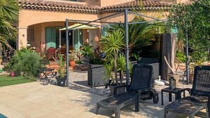 Eine Terrasss mit Lounge-Möbeln, einer Pergola und Pflanzen in Töpfen.