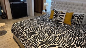 Ein Schlafzimmer mit einem großen Bett, einem Fernseher, einer Kommode und einer Lampe.