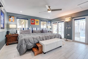 A bedroom with a bed, bedside table, lamp, and artwork on the wall. - Captain's Cove | Canalfront w/ Pool & Boat Lift (Key West)