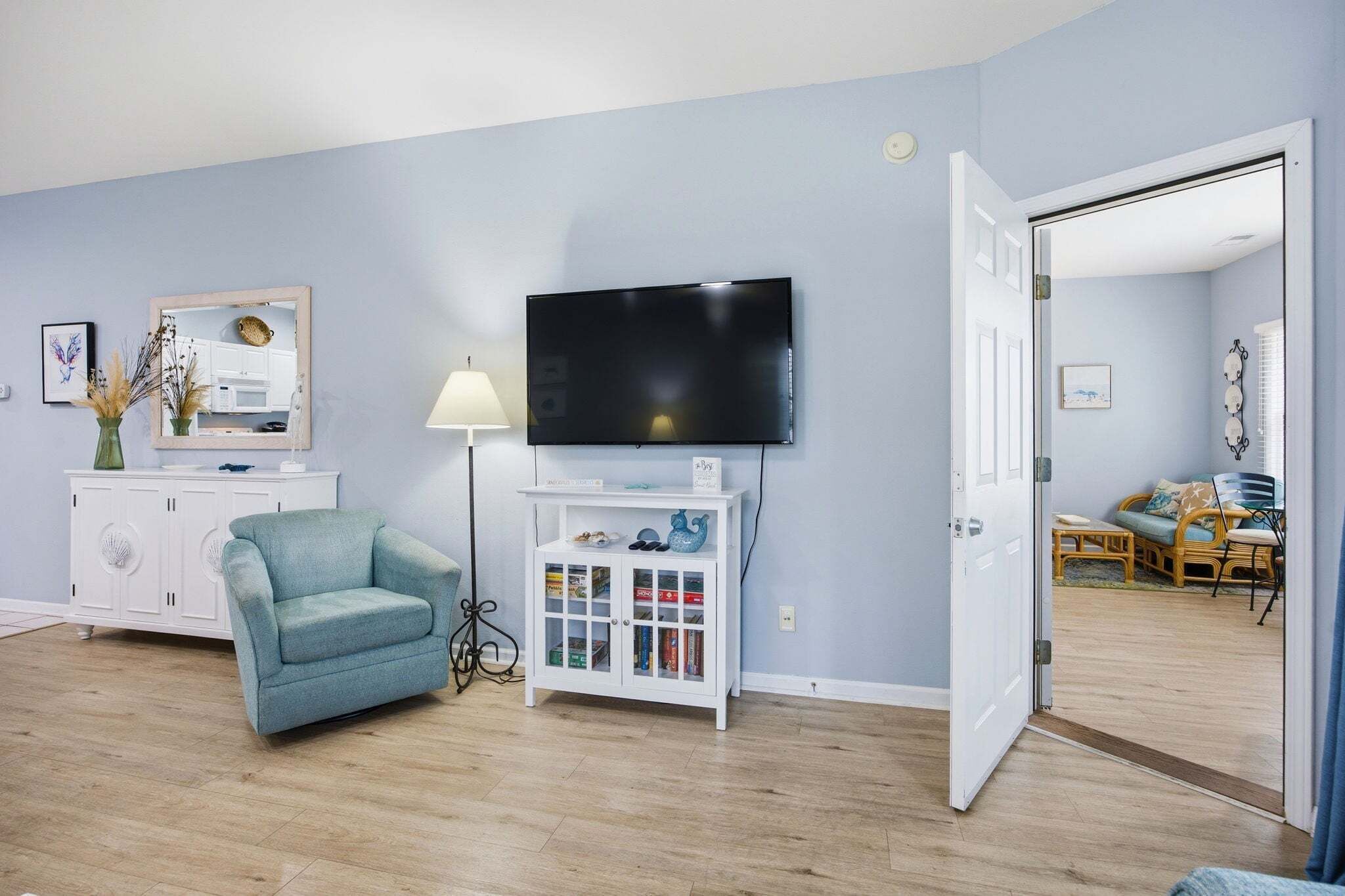 A living room with a sofa, TV, cabinet, and a door leading to another room.