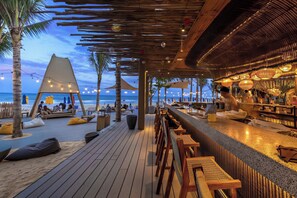 Eine Strandbar mit Holzdeck-Sitzgelegenheiten, einer Bar und Blick aufs Meer.