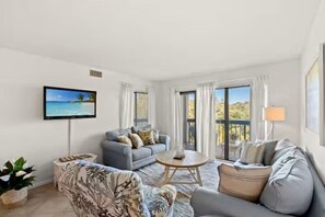 A living room with a sofa, a coffee table, a TV, and a view of the outdoors. - Oceanview Oasis with Pool-Beach! (Myrtle Beach)