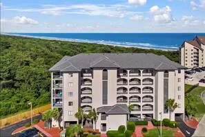 A multi-story hotel with balconies, a parking area, and a view of the ocean. - Oceanview Oasis with Pool-Beach! (Myrtle Beach)