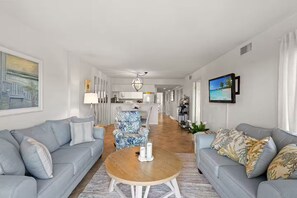 A modern living room with two grey sofas, a round wooden coffee table, and a kitchen in the background. - Oceanview Oasis with Pool-Beach! (Myrtle Beach)