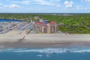 Eine Luftaufnahme eines Küstenhotels mit mehreren Gebäuden, einem Strand und einer Marina.
