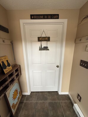 Una puerta con un cartel que dice 'Welcome to the Cabin', un letrero de 'Welcome' y una decoración con temática de oso.