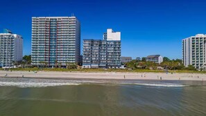 Ein Strandhotel mit mehreren Hochhäusern, einem Sandstrand und Blick auf den Ozean.
