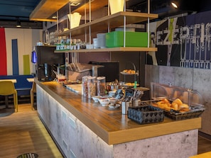 A buffet counter with various food items, utensils, and a seating area with chairs.
