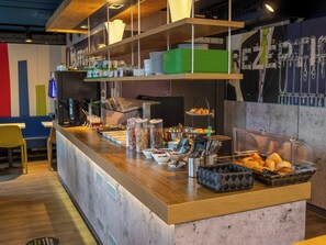A buffet counter with various food items, utensils, and a seating area with chairs. - B B Hotel Braunschweig West (Braunschweig)