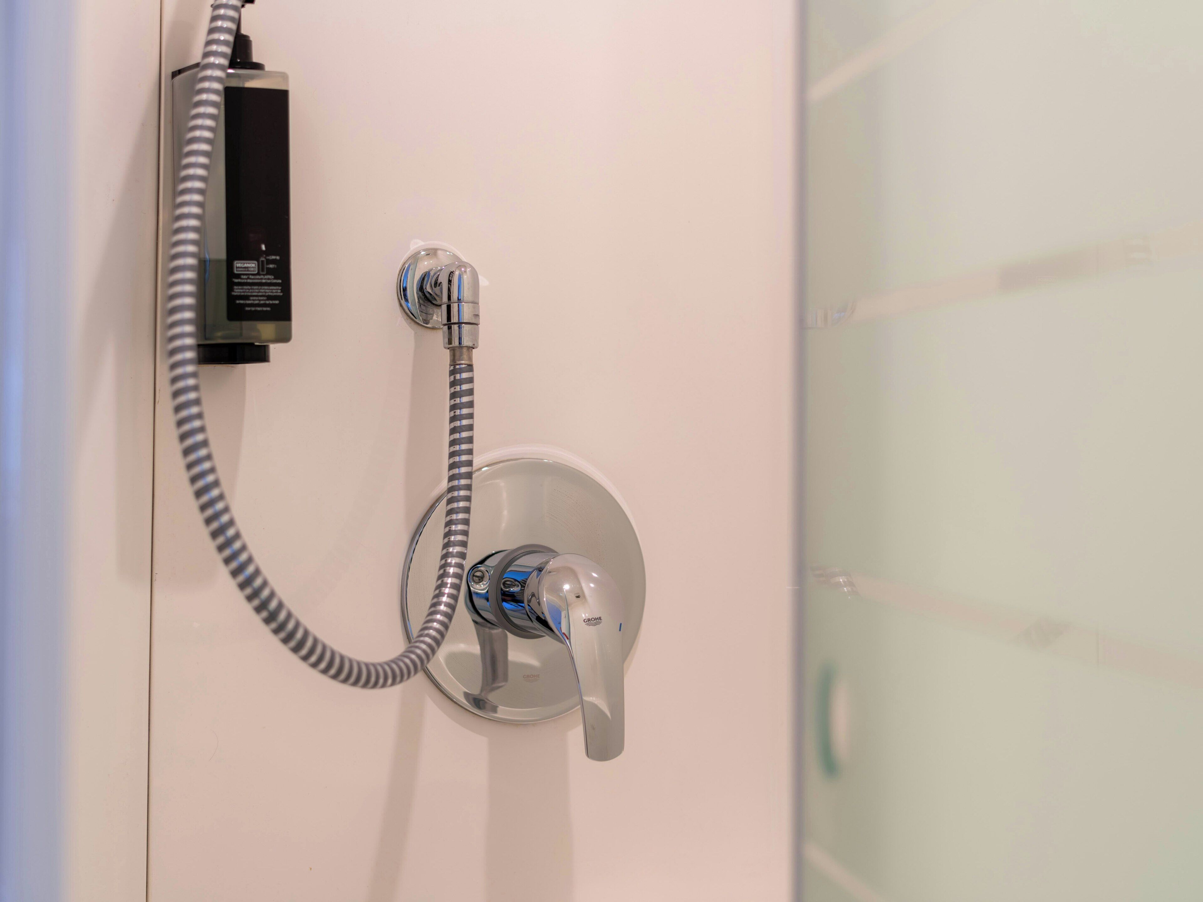 A shower with a handheld showerhead and a flexible hose connected to a power outlet.