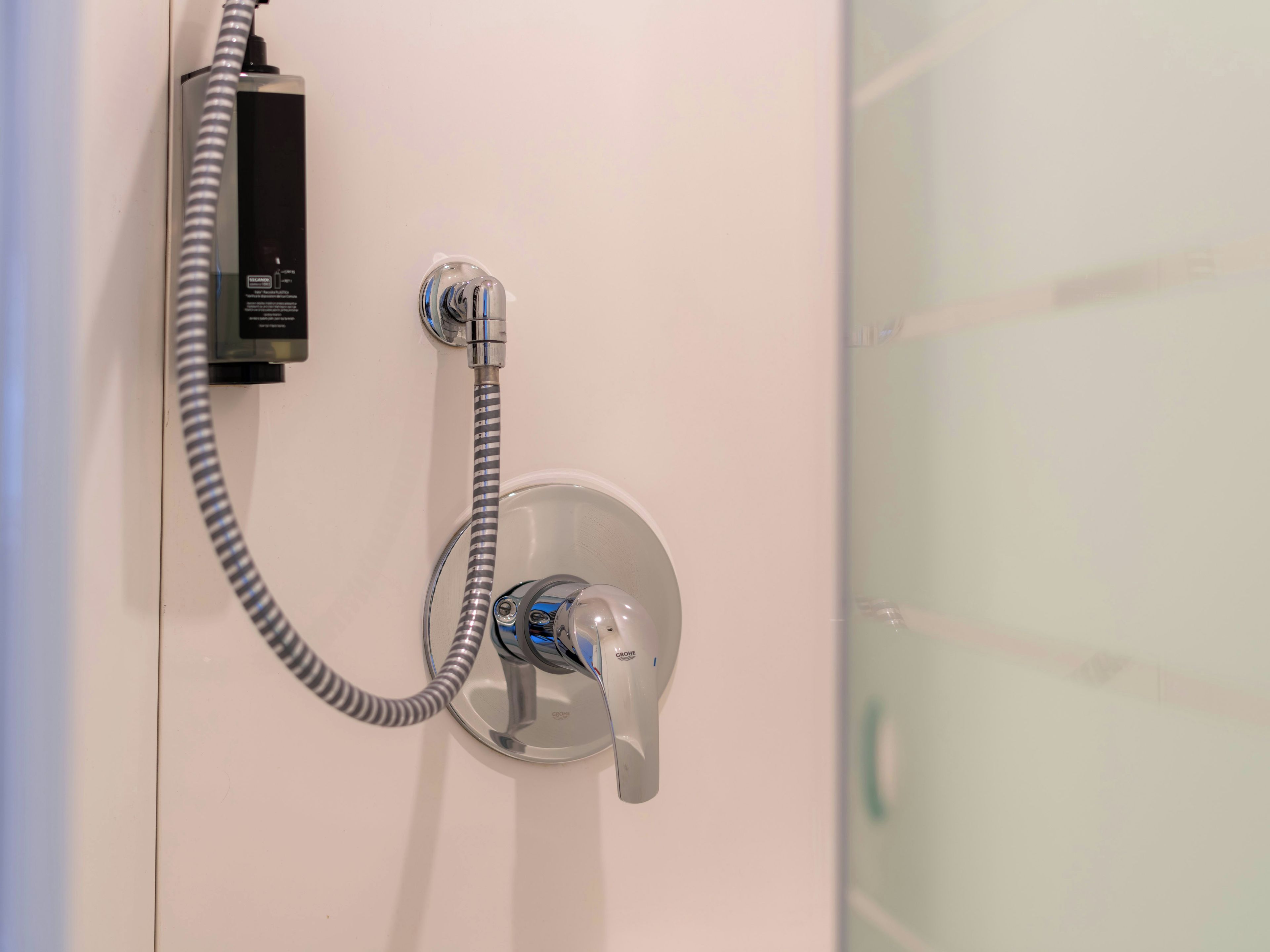 A shower with a handheld showerhead and a flexible hose connected to a power outlet.