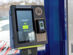 Quiosco de autoservicio para el registro de entrada con una pantalla que muestra un mensaje de bienvenida y opciones para acceder a las habitaciones.