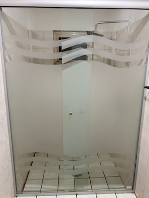 A glass-enclosed shower stall with a tiled floor and a visible showerhead.