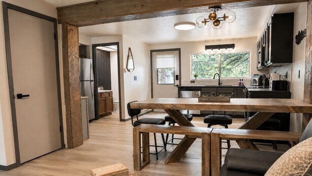 Una cucina moderna con un tavolo e sedie in legno, una zona pranzo con una panca e vista sull'esterno attraverso ampie finestre.