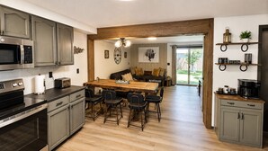 Eine moderne Küche mit Kochinsel, integrierten Geräten und einem Essbereich mit Holztisch und Stühlen.