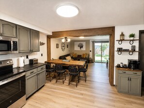 A modern kitchen with a central island, built-in appliances, and a dining area with a wooden table and chairs.