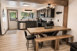 A kitchen with dark cabinets, a wooden dining table, and a bench.