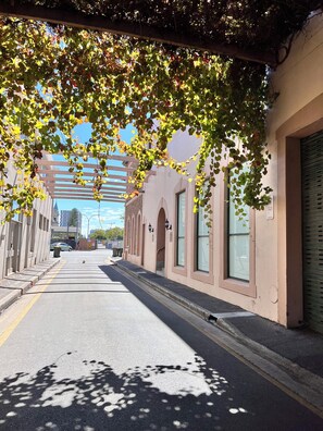 A street with buildings, a clear sky, and shadows on the pavement. - Exhotel city stay 428 (Adelaide)