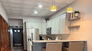 Una cocina moderna con una isla central, taburetes de madera y una lámpara colgante.