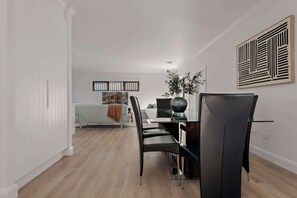 Un comedor moderno con una mesa de vidrio, sillas negras y un jarrón decorativo.