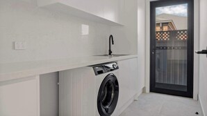 A compact laundry area with a washing machine, a sink, and a door leading to an outdoor area.