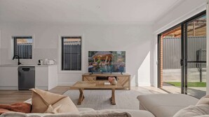 Una sala de estar moderna con una mesa de centro de madera, un sofá y un televisor que muestra una escena tropical.