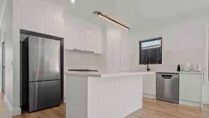 Una cocina moderna con armarios blancos, un refrigerador de acero inoxidable, un lavavajillas integrado y una isla central.