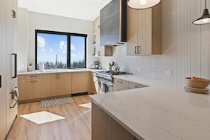 Une cuisine moderne avec des meubles en bois, une grande fenêtre et un plan de travail en marbre.