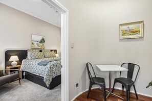 A bedroom with a bed, bedside table, lamp, and a painting on the wall.