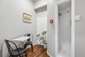 A small room with a white table, two chairs, a potted plant, a fire alarm, and a door.