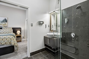 A modern bathroom with a large mirror, a sink, and a shower. - Chapel on Moray - studio room with bathroom and kitchenette (Dunedin)
