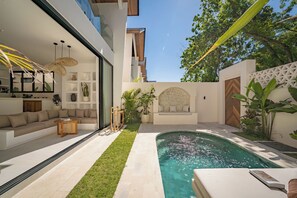 Un espacio exterior moderno con piscina, sofá y zona de comedor.