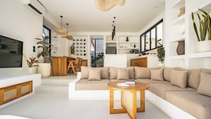 A modern living room with a sectional sofa, a round wooden coffee table, and a TV. - Uluwatu Surf Sanctuary Villa (Uluwatu)