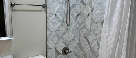 A bathroom with a shower, toilet, and sink, featuring geometric tile patterns.