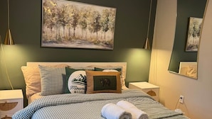 A bedroom with a bed, a ceiling fan, a painting, and a nightstand. - Fun 5 Bedroom Lakefront Cottage (Bethel)
