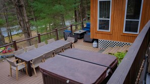 A deck with outdoor furniture, a hot tub, and a view of the lake. - Fun 5 Bedroom Lakefront Cottage (Bethel)