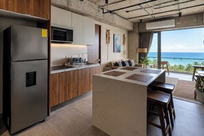 Une cuisine moderne équipée d’un réfrigérateur et d’un four à micro-ondes intégrés, ainsi que d’un coin repas offrant une vue sur l’océan.